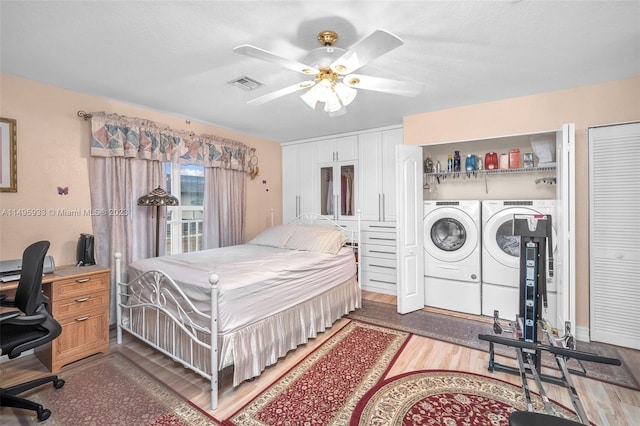 bedroom featuring washing machine and dryer, multiple closets, wood-type flooring, and ceiling fan