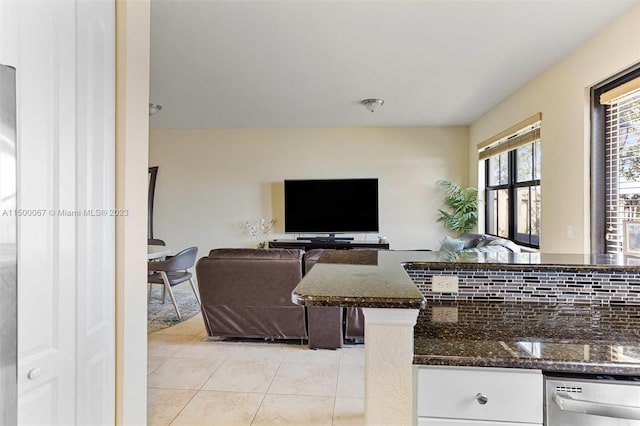 kitchen with dishwasher, backsplash, white cabinets, dark stone countertops, and light tile patterned floors