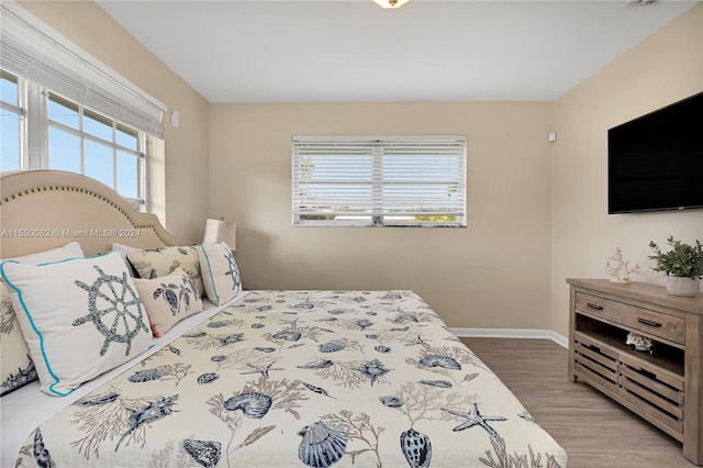 bedroom with multiple windows and hardwood / wood-style flooring