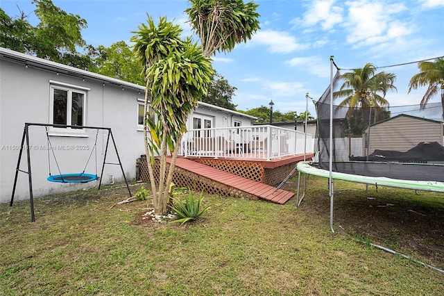 view of yard featuring a trampoline and a wooden deck