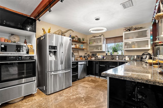 kitchen with stainless steel appliances, dark stone countertops, and sink