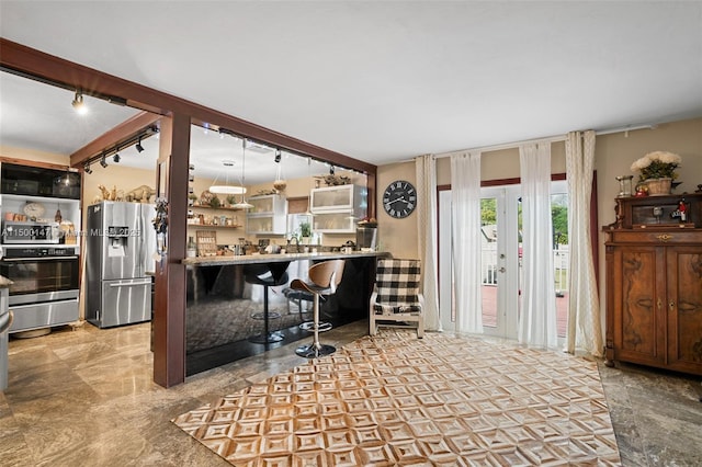 kitchen featuring stainless steel refrigerator with ice dispenser, stove, rail lighting, and a kitchen bar