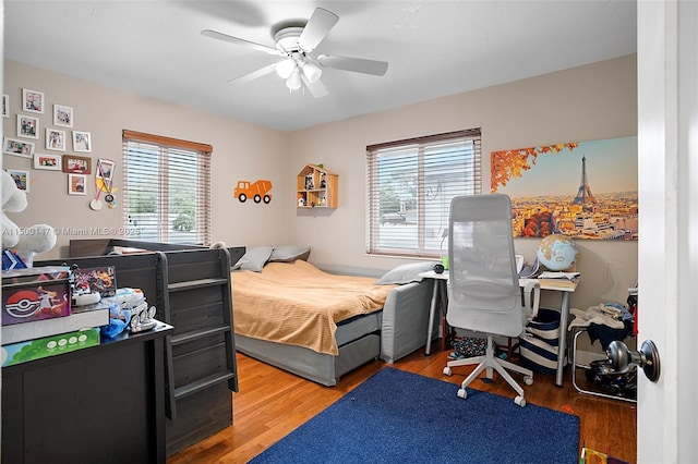 bedroom featuring ceiling fan, multiple windows, and hardwood / wood-style flooring