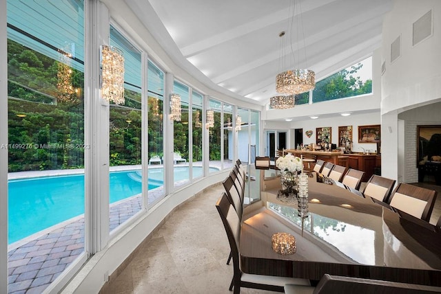 sunroom featuring vaulted ceiling with beams, a wealth of natural light, and a notable chandelier