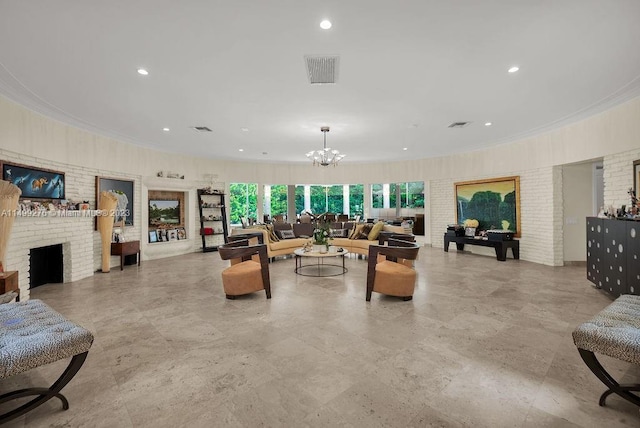 living room featuring a brick fireplace, crown molding, and an inviting chandelier