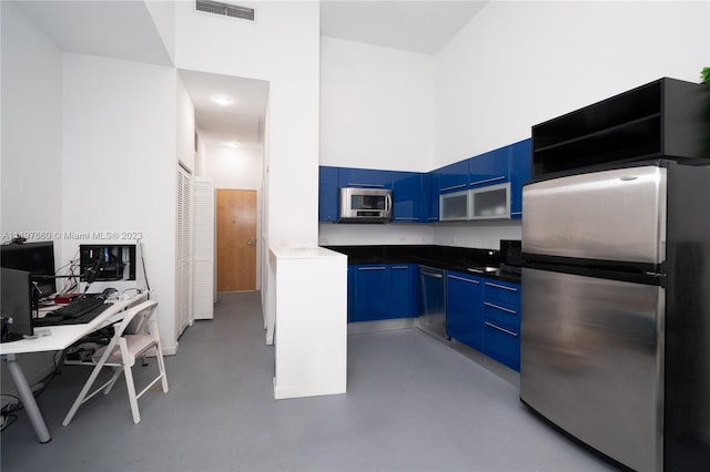 kitchen featuring blue cabinets, a high ceiling, and appliances with stainless steel finishes