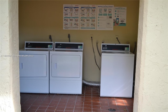 laundry room featuring washer and clothes dryer and dark tile patterned floors