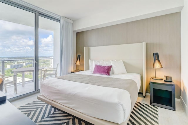 bedroom featuring a wall of windows, light hardwood / wood-style floors, and access to exterior