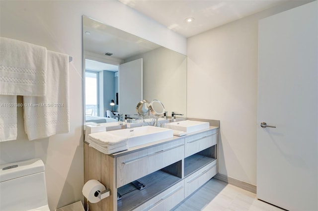 bathroom with dual bowl vanity and toilet