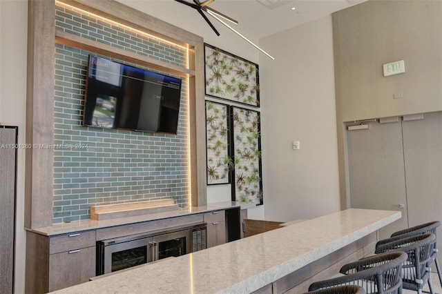 kitchen featuring a breakfast bar, beverage cooler, kitchen peninsula, and decorative backsplash