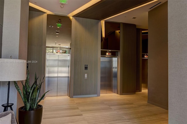 hall with light hardwood / wood-style floors and elevator