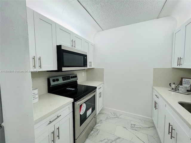 kitchen with white cabinetry, light tile patterned flooring, a textured ceiling, and stainless steel appliances