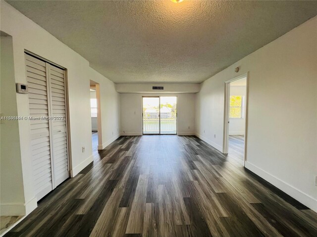 spare room featuring a textured ceiling and dark wood-type flooring