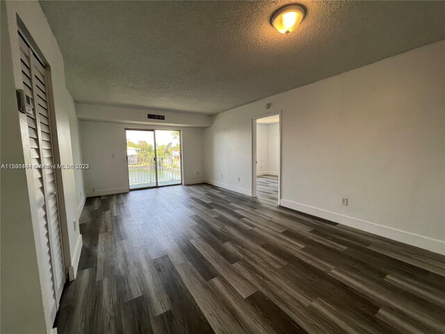 spare room with dark hardwood / wood-style flooring and a textured ceiling