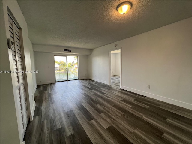 empty room featuring dark hardwood / wood-style floors and a textured ceiling