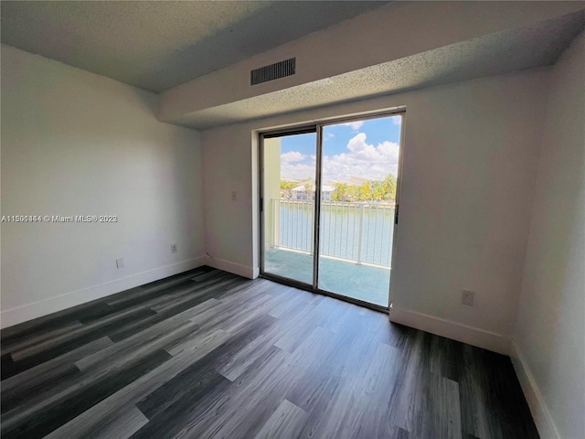 empty room with a water view and dark wood-type flooring