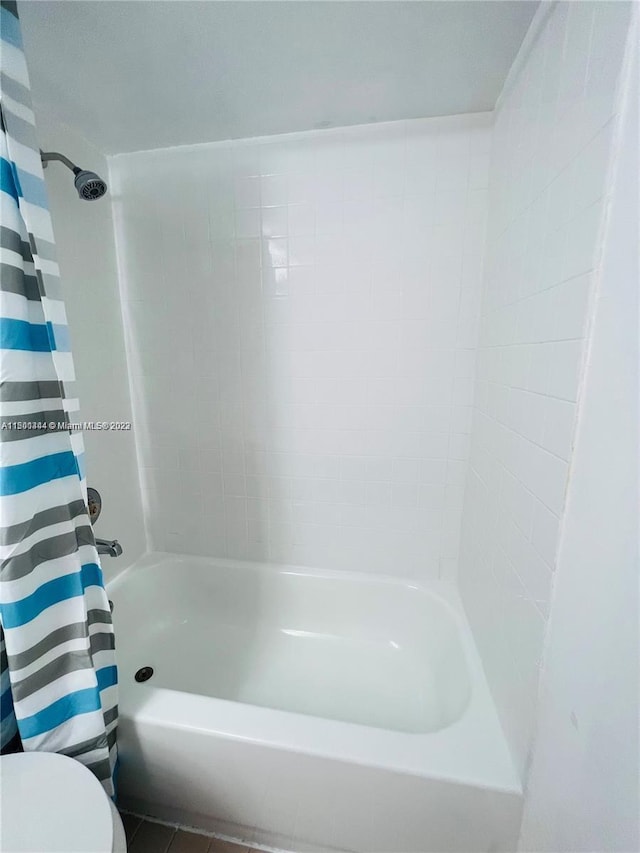 bathroom with toilet, tile patterned floors, and shower / bath combo with shower curtain