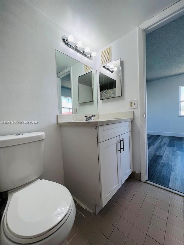 bathroom featuring vanity, toilet, wood-type flooring, and plenty of natural light