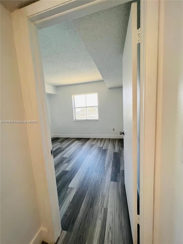 empty room with dark hardwood / wood-style floors and a textured ceiling