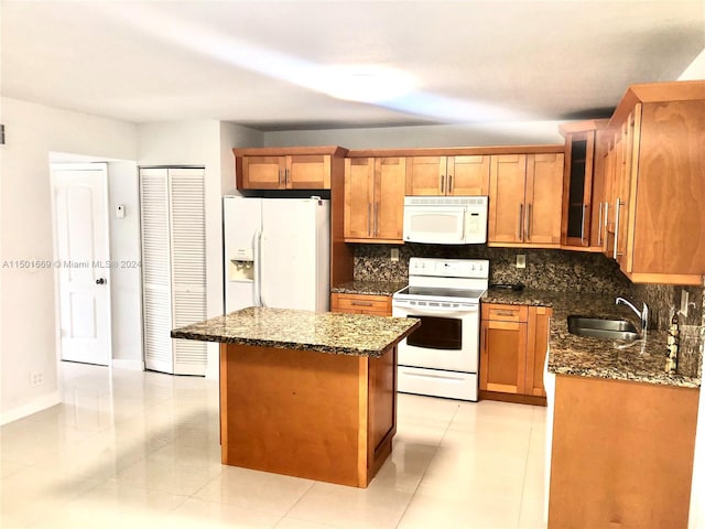 kitchen featuring dark stone counters, backsplash, white appliances, and sink