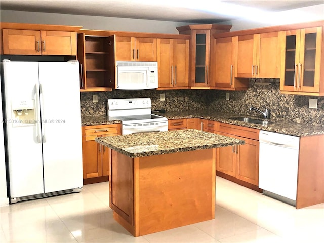 kitchen featuring light tile flooring, a kitchen island, white appliances, and dark stone countertops