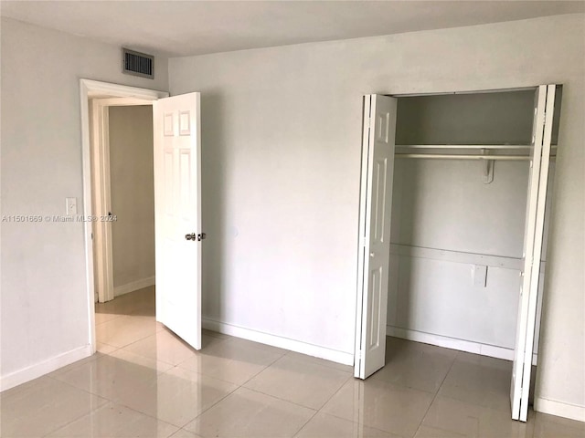 unfurnished bedroom with a closet and light tile floors