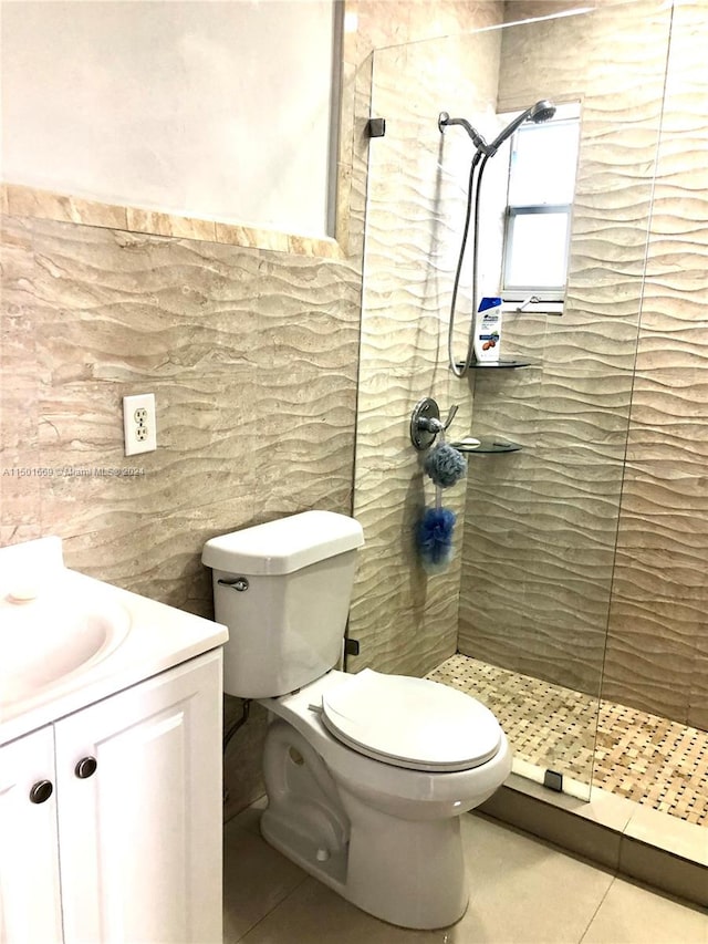 bathroom featuring tile walls, toilet, a tile shower, tile flooring, and vanity