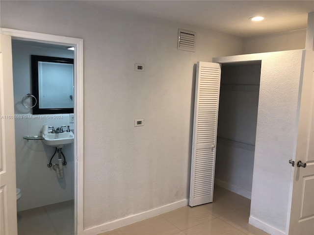 bedroom with a closet, sink, and light tile flooring