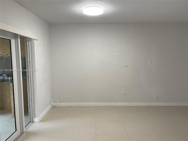 spare room with a textured ceiling and light tile floors