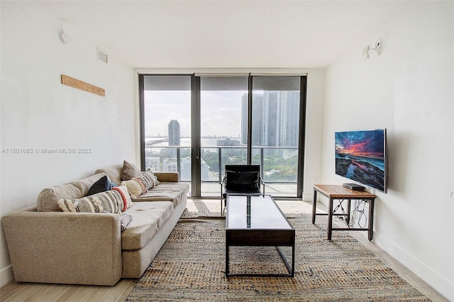 living room with plenty of natural light, floor to ceiling windows, and light hardwood / wood-style floors