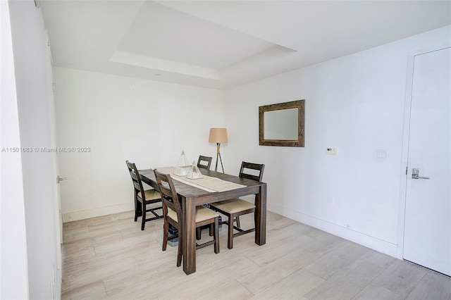 dining room with a raised ceiling and light hardwood / wood-style flooring