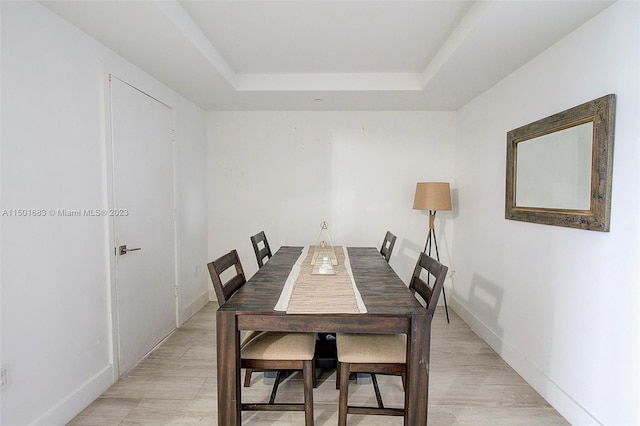 dining room with a raised ceiling and light hardwood / wood-style flooring