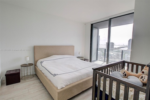 bedroom featuring floor to ceiling windows, access to exterior, and light hardwood / wood-style flooring