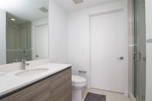 bathroom with an enclosed shower, vanity, tile floors, and toilet