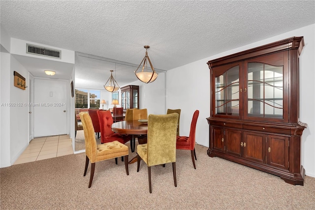 dining space with light carpet and a textured ceiling