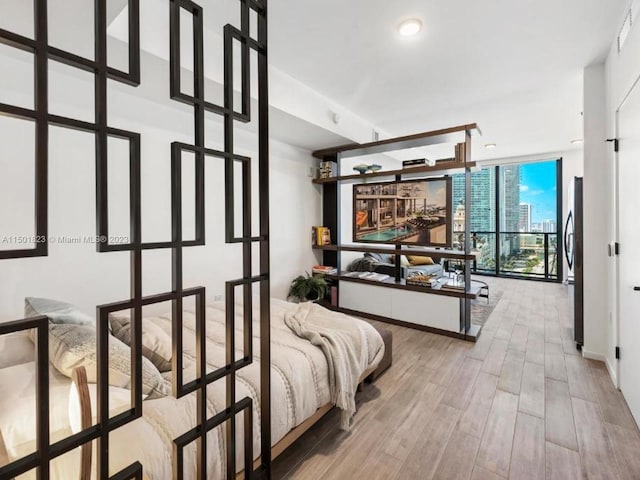 bedroom featuring fridge, expansive windows, and light hardwood / wood-style flooring