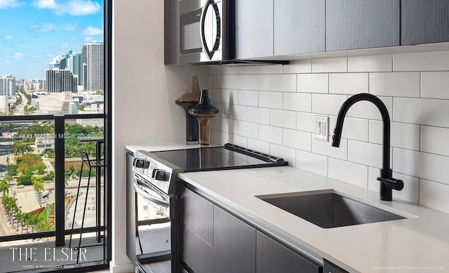 kitchen with backsplash, gray cabinets, sink, and stainless steel appliances