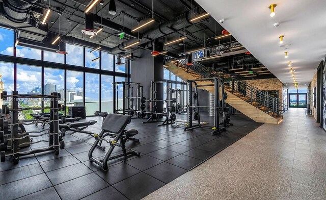 exercise room with a wall of windows, dark tile floors, and a towering ceiling