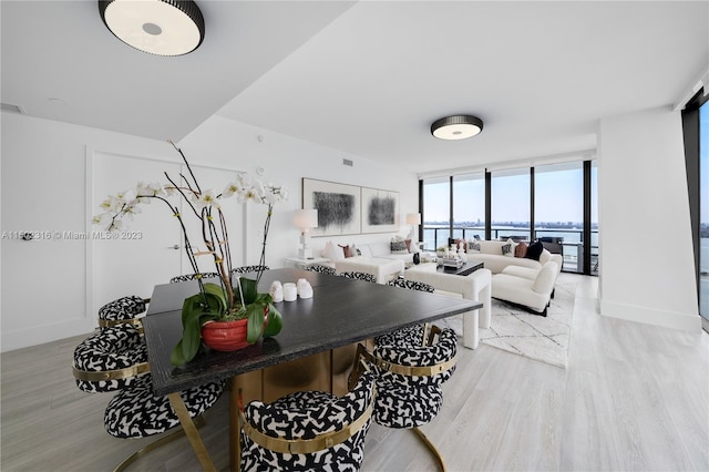 living room with light hardwood / wood-style floors, floor to ceiling windows, and a water view