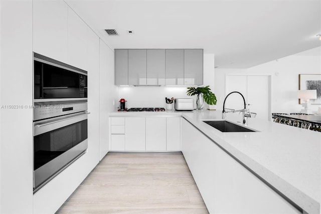 kitchen featuring sink, oven, white cabinetry, gas stovetop, and built in microwave