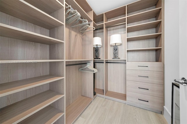 walk in closet with light hardwood / wood-style floors