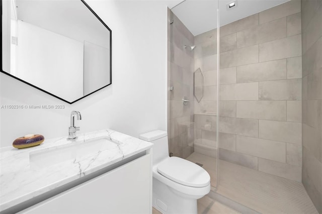 bathroom with tiled shower, vanity, and toilet