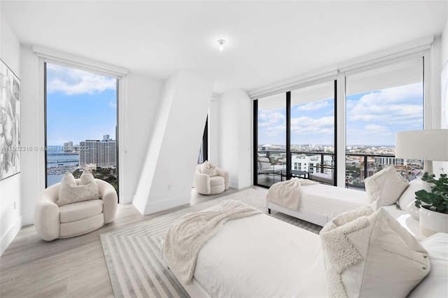 bedroom featuring access to outside, a wall of windows, and light hardwood / wood-style flooring