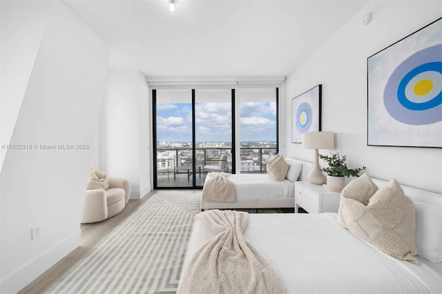 bedroom with a wall of windows, access to exterior, and light hardwood / wood-style flooring