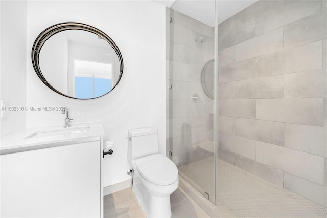 bathroom with a tile shower, vanity, and toilet