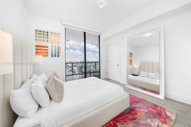 bedroom with floor to ceiling windows, access to exterior, and hardwood / wood-style floors