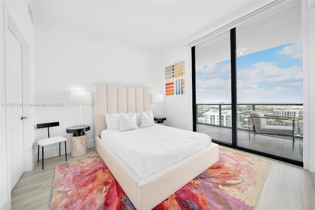 bedroom with a wall of windows, light hardwood / wood-style floors, and access to exterior