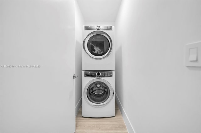 clothes washing area featuring light hardwood / wood-style flooring and stacked washer and clothes dryer