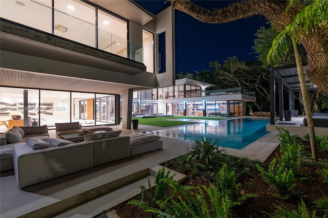 pool at night featuring outdoor lounge area