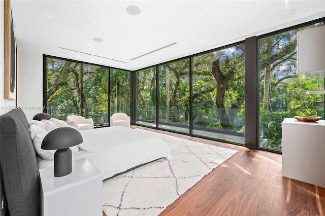 bedroom featuring hardwood / wood-style flooring, expansive windows, access to exterior, and multiple windows